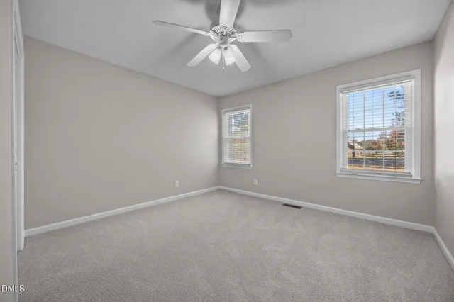 an empty room with a fan & a window