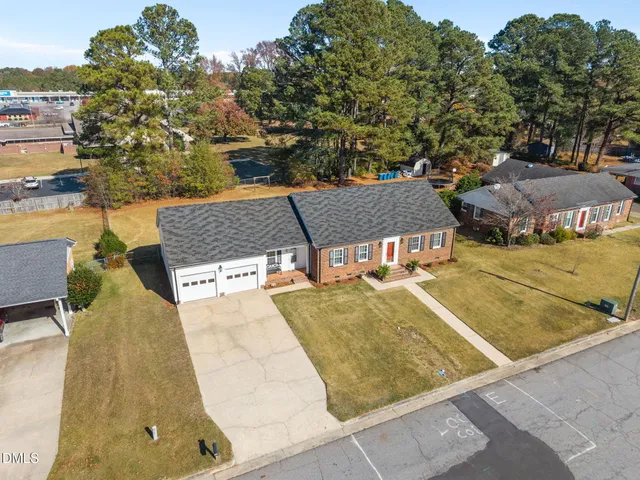 an aerial view of a house with swimming pool and large trees