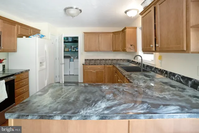 a kitchen with granite countertop a sink a stove and a wooden cabinets