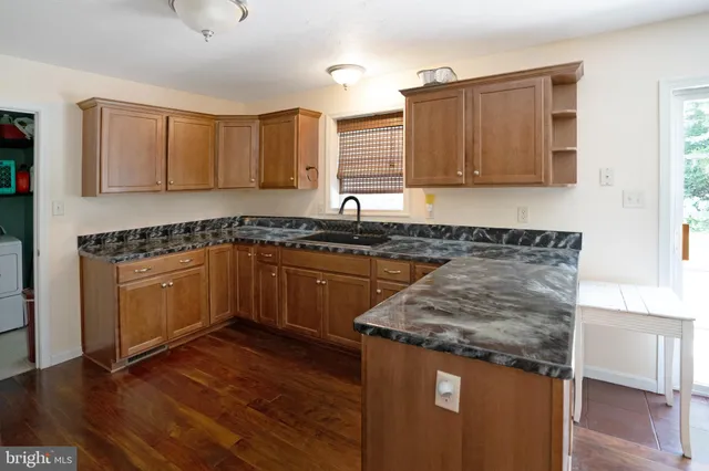 a kitchen with granite countertop a sink a counter top space and cabinets