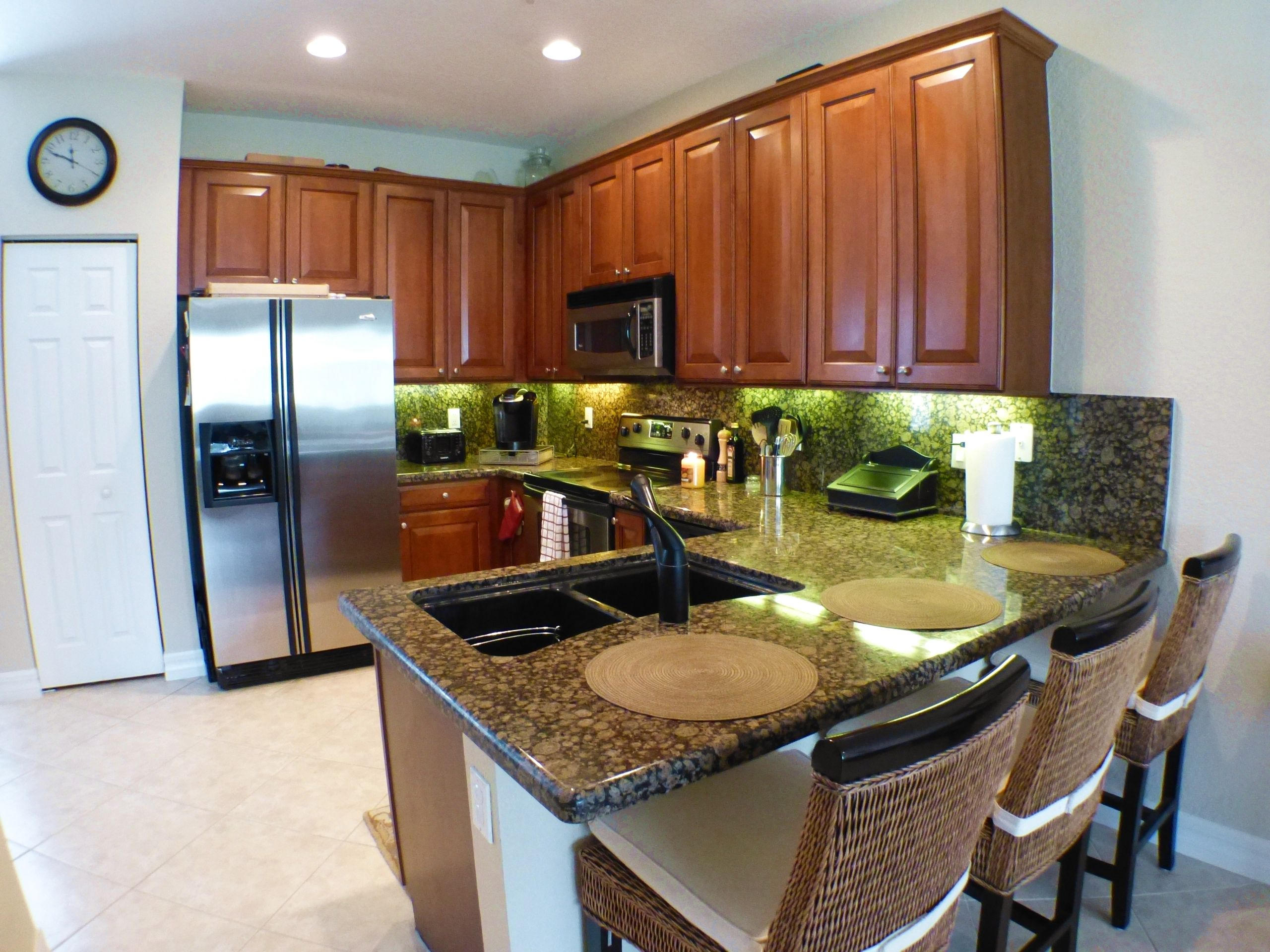 1826 Northwest 9th Street Boca Raton, FL 33431 - Photo 8 of 22 a kitchen with granite countertop a table chairs and a refrigerator