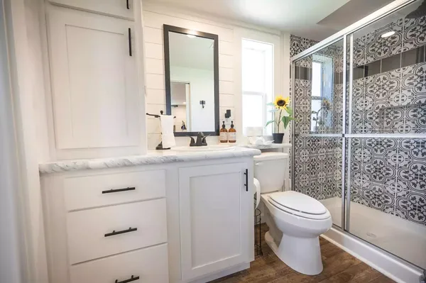 a bathroom with a granite countertop sink a large mirror a toilet and a bathtub