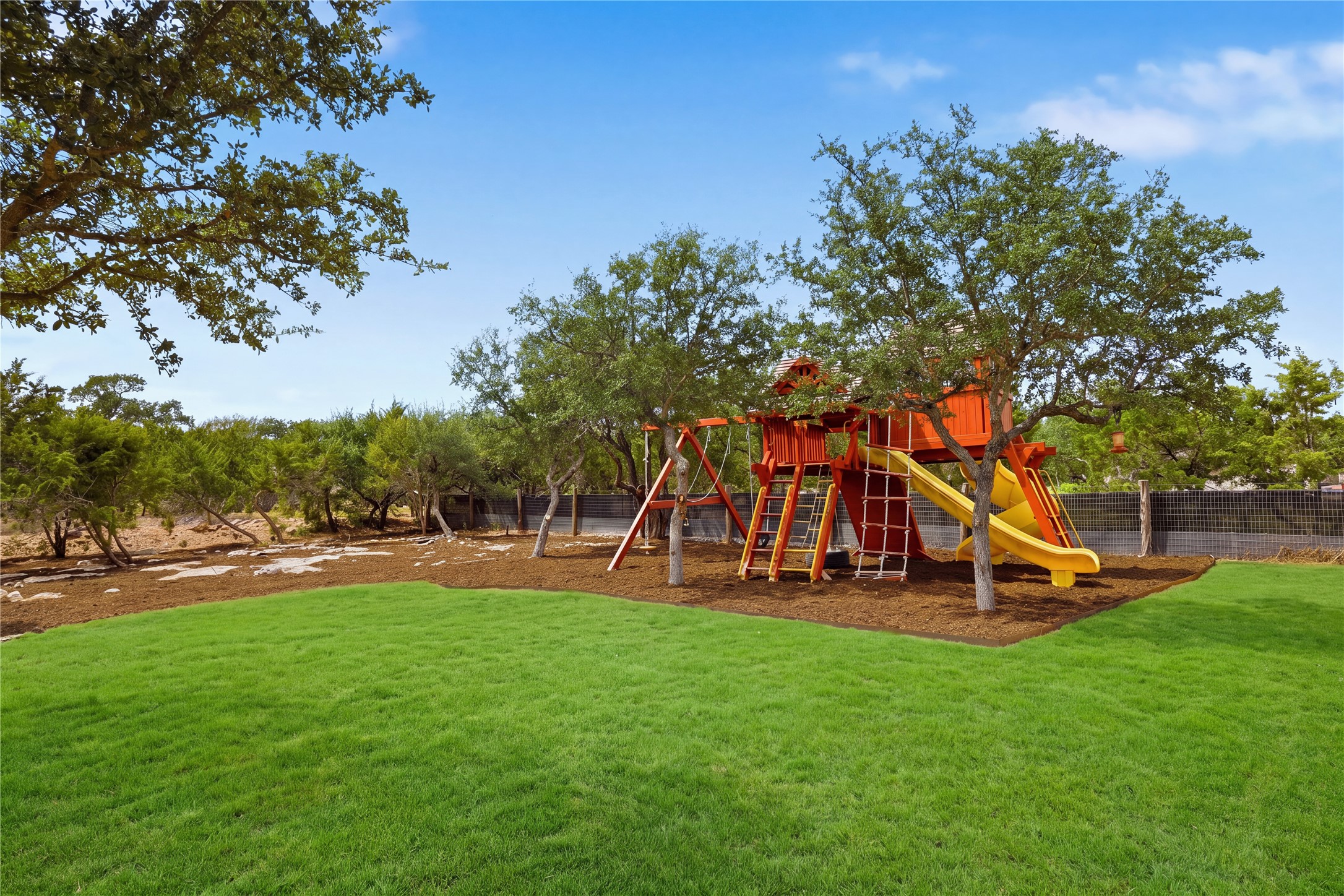 449 Ranch Falls Fair Oaks Ranch, TX 78015 - Photo 11 of 39 Mature trees shade a designated play area bordering a sprawling, manicured lawn.