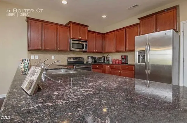 a kitchen with granite countertop a refrigerator sink and cabinets