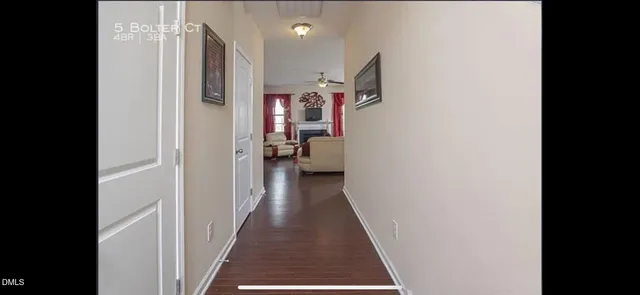 a view of a hallway with wooden floor and a bathroom