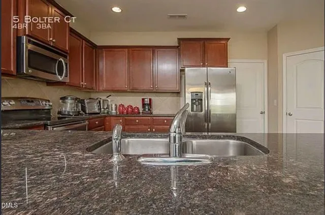 a kitchen with kitchen island granite countertop a sink refrigerator and microwave