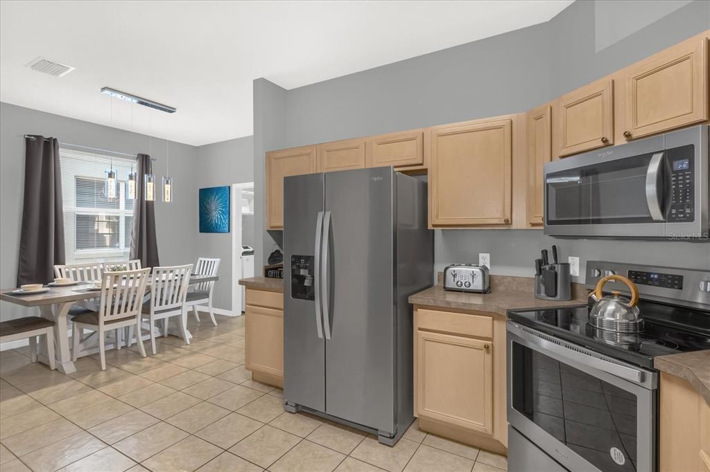 246 Montara Drive Davenport, FL 33897 - Photo 13 of 37 a kitchen with cabinets stainless steel appliances and a dining table view