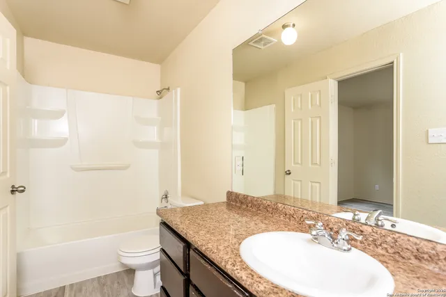 a bathroom with a granite countertop sink toilet a mirror and shower