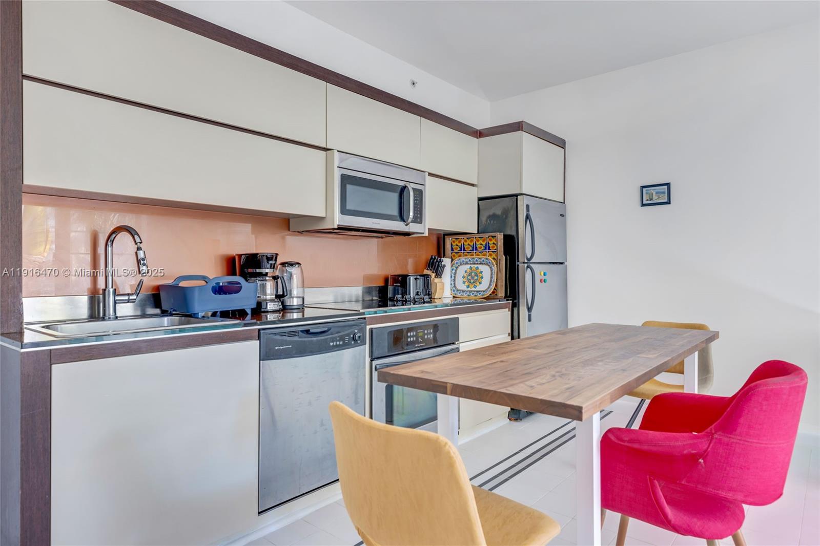 435 21st Street, Unit 311 Miami Beach, FL 33139 - Photo 14 of 40 a kitchen with stainless steel appliances granite countertop a dining table chairs sink and cabinets