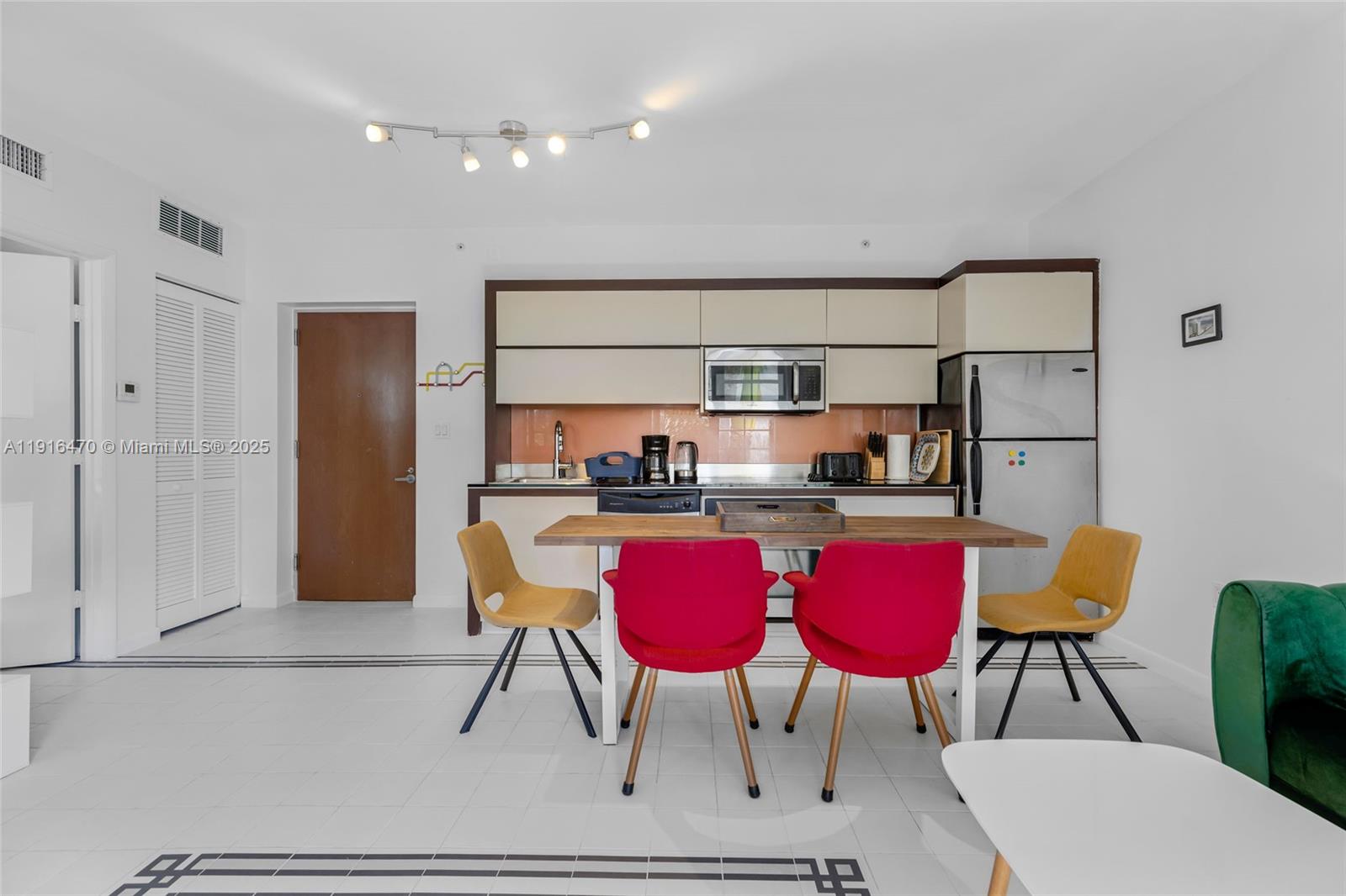 435 21st Street, Unit 311 Miami Beach, FL 33139 - Photo 17 of 40 a kitchen with stainless steel appliances kitchen island granite countertop a dining table chairs and refrigerator