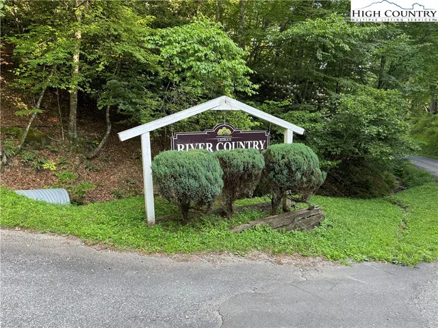 a sign board with a house and yard at the back