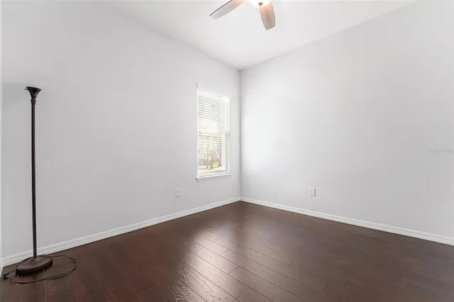 an empty room with wooden floor cabinet and windows