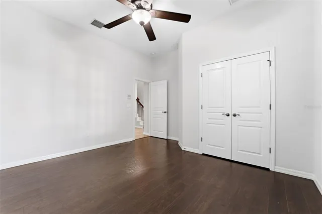 an empty room with closet and a ceiling fan