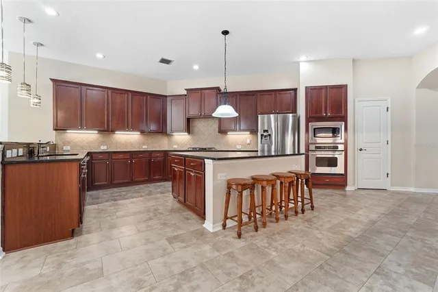 a kitchen with stainless steel appliances granite countertop a stove top oven a refrigerator and a sink