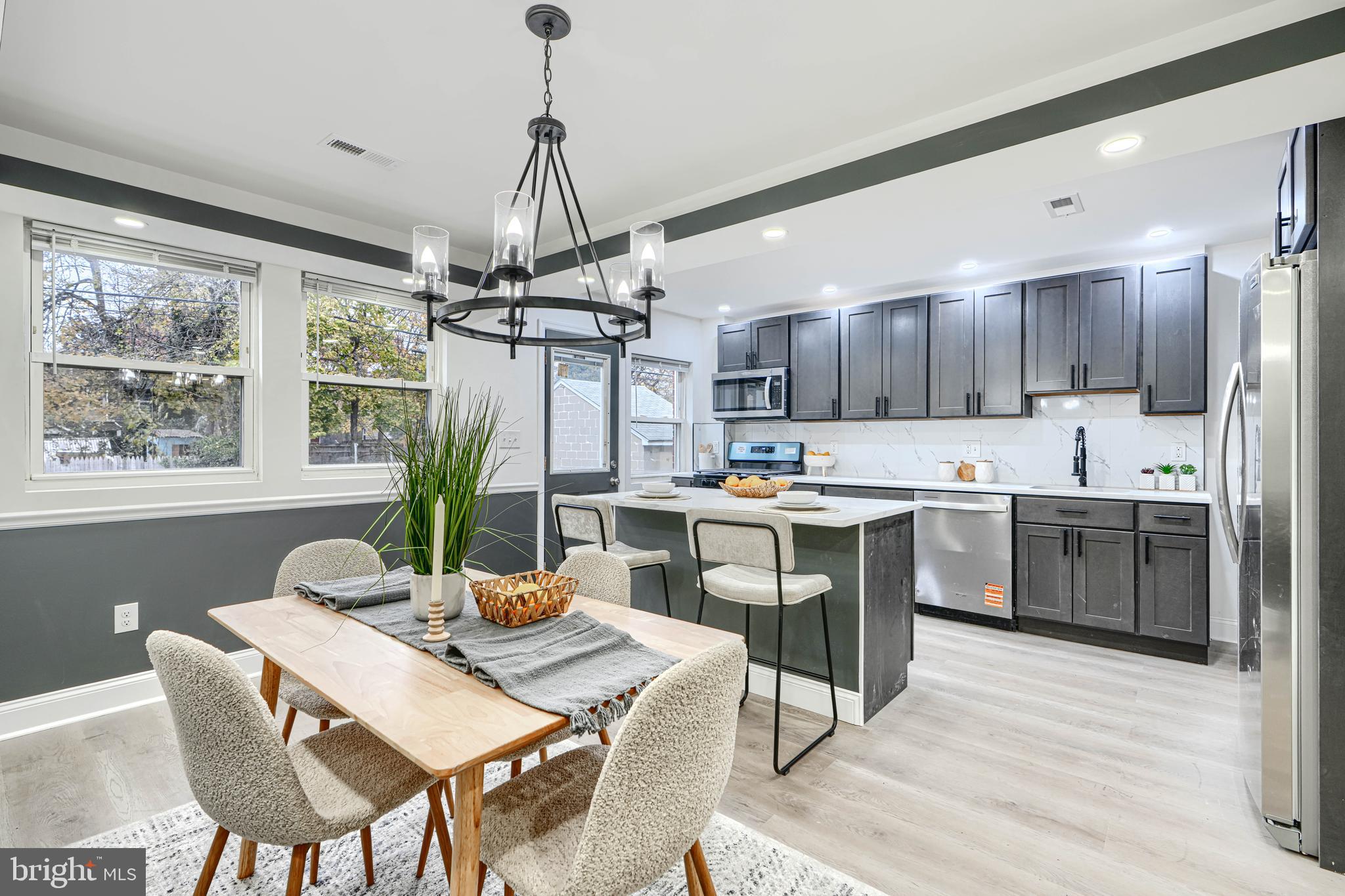 718 Benninghaus Road Baltimore, MD 21212 - Photo 3 of 40 a kitchen with stainless steel appliances kitchen island granite countertop a sink dishwasher a stove a refrigerator with a dining table and chairs with wooden floor