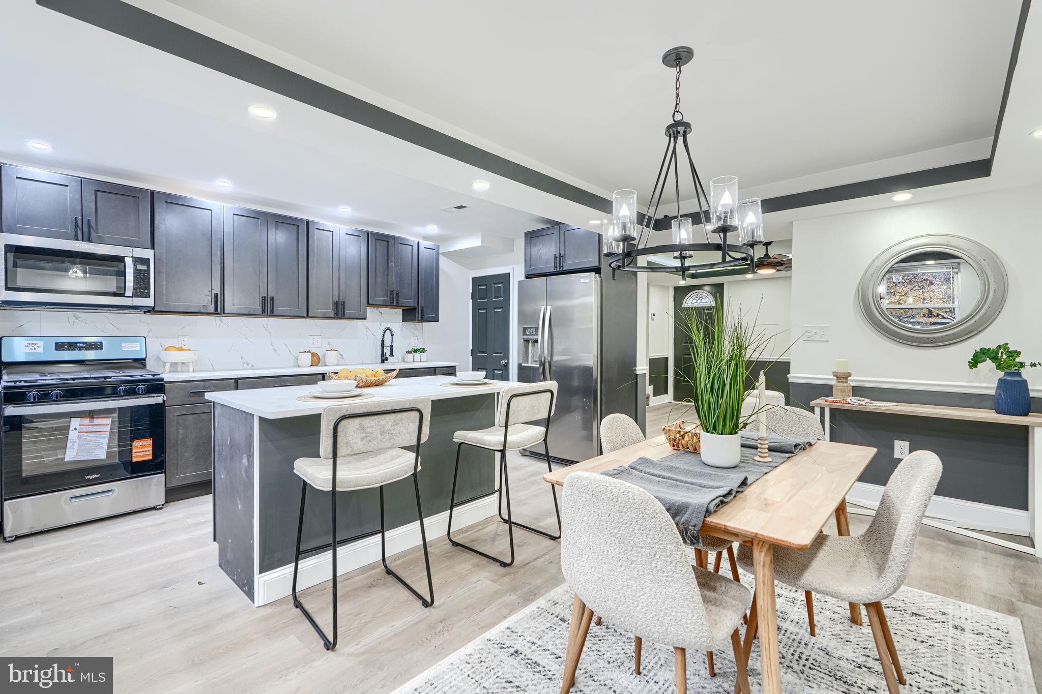 718 Benninghaus Road Baltimore, MD 21212 - Photo 9 of 40 a kitchen with stainless steel appliances granite countertop a stove top oven a refrigerator a kitchen island a dining table and chairs