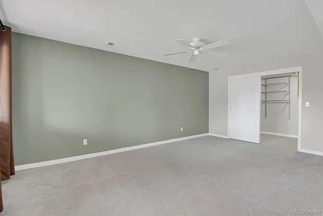 an empty room with closet and a ceiling fan