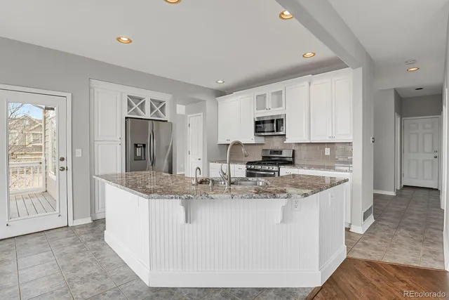 a large kitchen with granite countertop a sink a counter top space and stainless steel appliances