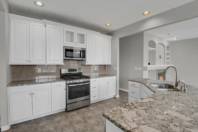 a kitchen with granite countertop a stove sink and cabinets