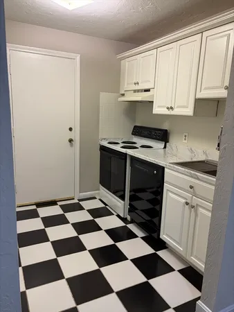 a kitchen with a checkered floor and white cabinets