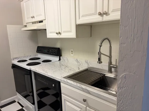 a kitchen with granite countertop a stove sink and cabinets