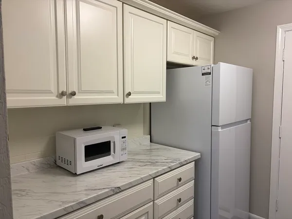 a kitchen with white cabinets and refrigerator