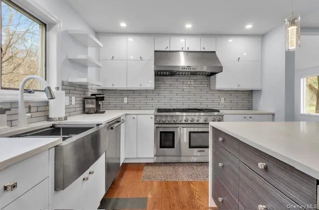 a kitchen with stainless steel appliances granite countertop a sink a stove and a refrigerator