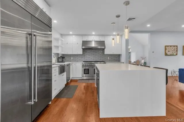 a large kitchen with stainless steel appliances kitchen island a large counter top and a refrigerator