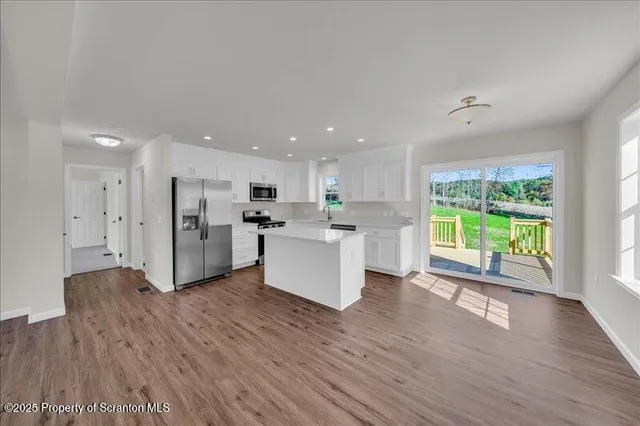 a view of kitchen with kitchen island wooden floors appliances and cabinets