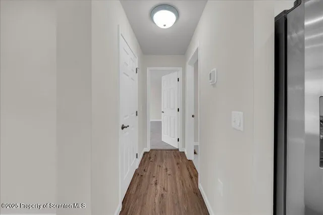 a view of a hallway with wooden floor and a bathroom