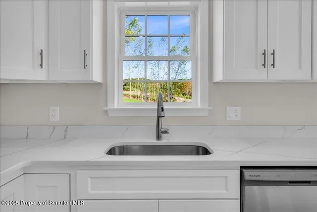 a kitchen with stainless steel appliances granite countertop white cabinets and a sink