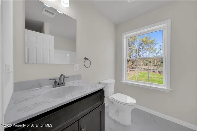 a bathroom with a granite countertop sink a toilet and a window