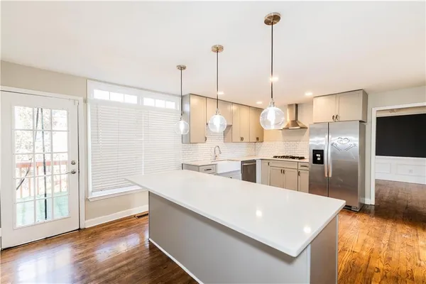 a kitchen with stainless steel appliances a stove a sink a refrigerator a center island a stove and a refrigerator