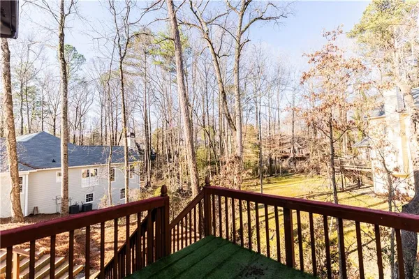 a view of a white house with a large tree and wooden fence
