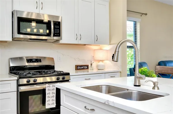 a kitchen with stainless steel appliances granite countertop a sink a stove and microwave with wooden floor