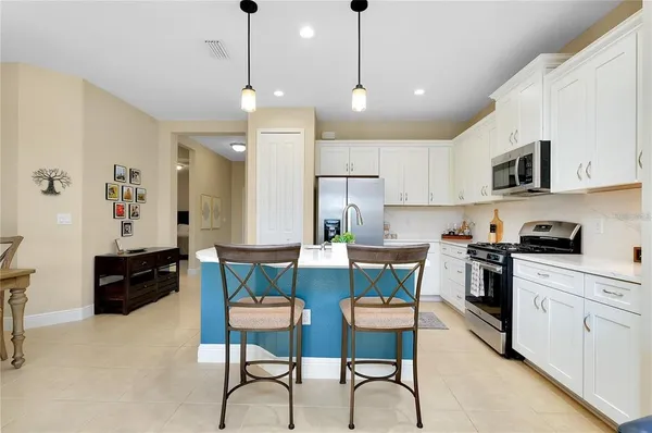 a kitchen with stainless steel appliances granite countertop a stove a sink a refrigerator a stove a microwave oven a dining table and chairs with wooden floor