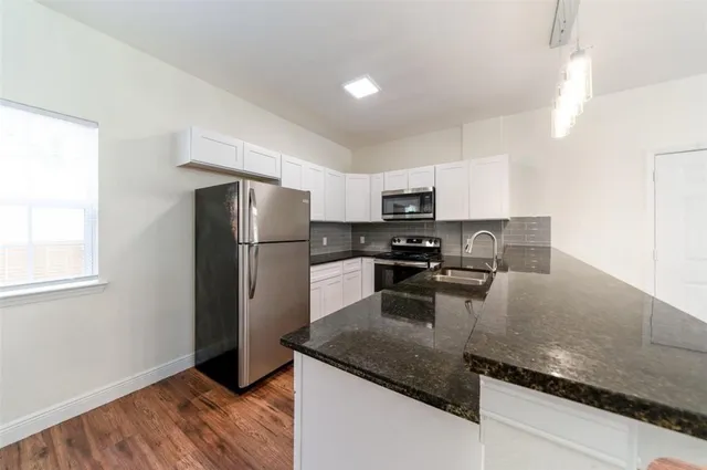 a kitchen with granite countertop stainless steel appliances a refrigerator a stove a sink a microwave and island