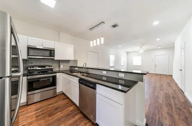 a kitchen with stainless steel appliances granite countertop a stove a sink and a refrigerator