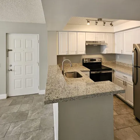 a kitchen with stainless steel appliances granite countertop a sink a stove and a refrigerator