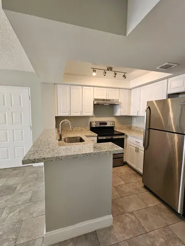 a kitchen with granite countertop a sink a counter top space and stainless steel appliances