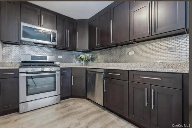 a kitchen with granite countertop wooden cabinets stainless steel appliances and a sink