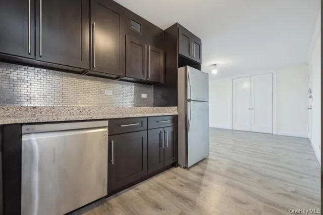 a kitchen with stainless steel appliances granite countertop a refrigerator a sink dishwasher and wooden cabinets with wooden floor