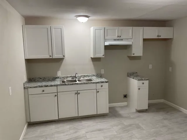 a kitchen with granite countertop white cabinets and a sink