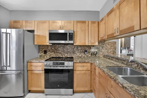 a kitchen with granite countertop a sink stove and refrigerator