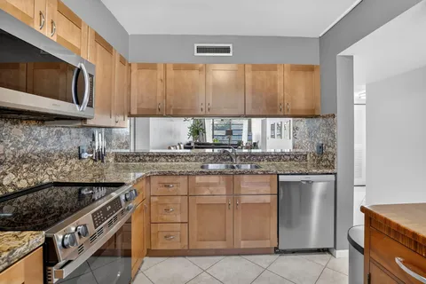 a kitchen with stainless steel appliances granite countertop a stove a sink and a microwave