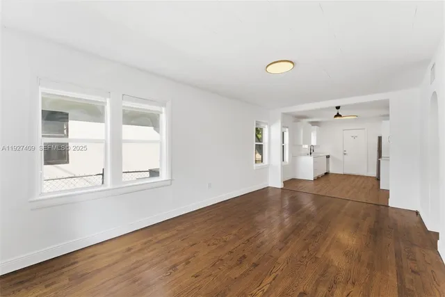 a view of empty room with wooden floor and fan