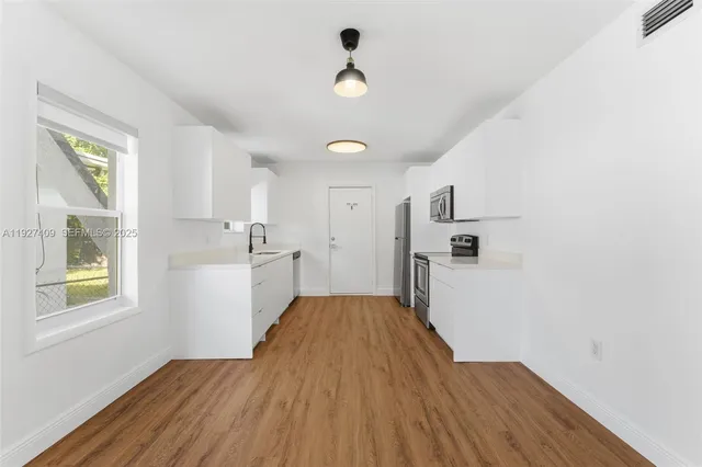 a view of a kitchen from the hallway with a window