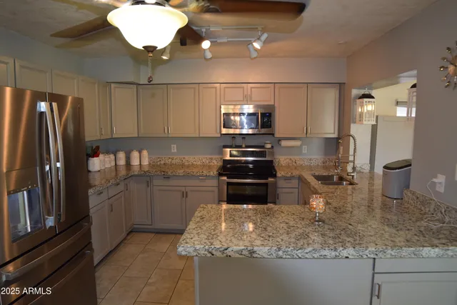 a kitchen with stainless steel appliances granite countertop a sink a stove and a refrigerator with cabinets