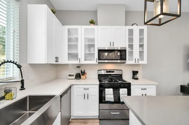 a kitchen with stainless steel appliances a stove a sink and white cabinets