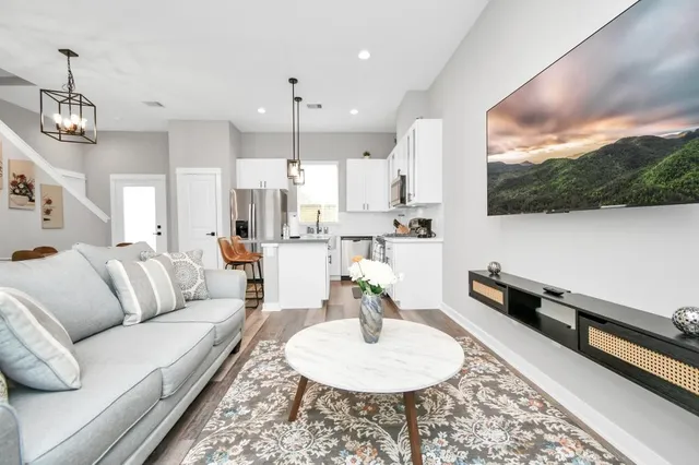 a living room with furniture kitchen view and a wooden floor